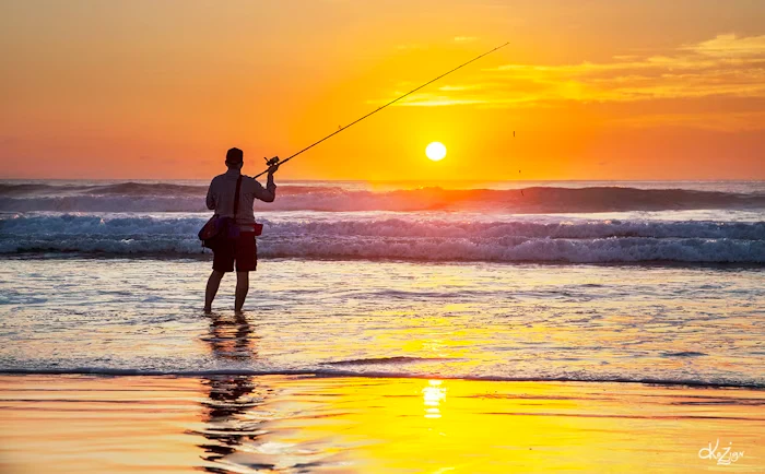 An angler fishing from a beach at sunset in Australia